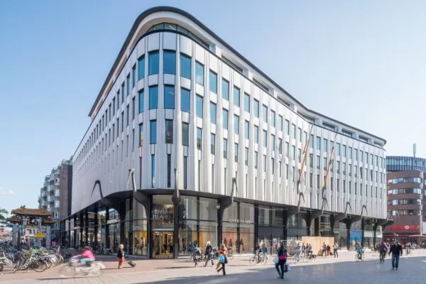 Winkelpand met moderne gevel aan de Grote Marktstraat in Den Haag, met voorbijgangers en winkels zoals River Island en MediaMarkt.